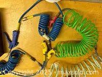 Multiple coiled hoses and blow guns on wooden surface