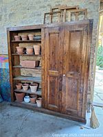 Full view of cabinet showing open shelves with pots and closed double doors