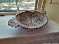 Top angle of entire wooden colander on windowsill