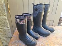 Two pairs black rubber boots on table