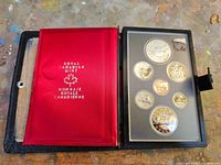 Closed case showing coins in plastic lens and red satin panel