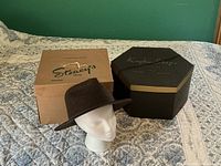 Fedora on display head beside two hat boxes