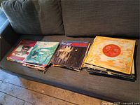 Three stacks of vinyl LPs on sofa showing assortment and quantity