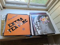 Stack of LPs showing George Harrison Extra Texture and floral portrait album