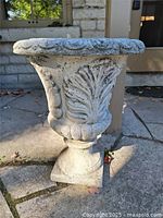 Full view of fiberglass urn planter showing decorative rim, leaf relief and pedestal base