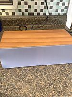 Front and top view of Audioengine speaker showing walnut cabinet and grey grille