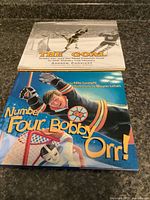 Two hockey books stacked: The Goal on top, Number Four, Bobby Orr! beneath