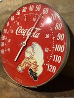 Full view of red Coca-Cola round thermometer showing scale and Sprite Boy graphic