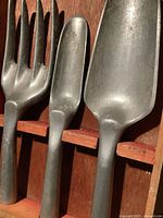Close-up of three cast aluminum garden tools showing shape and finish