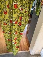 Close view of pant leg showing Grinch Santa print on green fleece