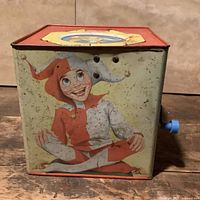 front and side of metal Jack-in-the-Box showing jester graphic and rust