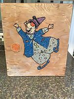 Full view of square beaded clown artwork on wood panel