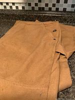 Folded brown coveralls showing fabric and snaps