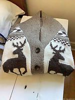 Folded sweater showing front button closure and shawl collar