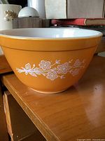 Side view of Pyrex golden-orange bowl with white floral motif