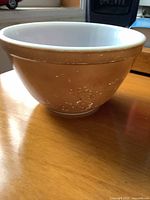 Side view of brown Pyrex bowl showing white interior and exterior wear