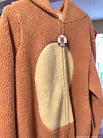 Full view of brown fleece onesie with cream belly and tag