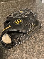 Full view of folded Wilson first baseman glove showing exterior logos and lacing