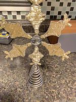 Front view of gold beaded metal star tree topper with spring base