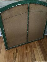 Back of arched wooden sash showing green painted frame, central mullion, backing board, wire hanger