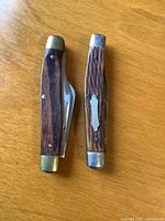 Both closed folding knives side by side showing wood handles and brass bolsters