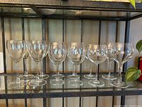 Ten of the twelve clear glass wine glasses on shelf