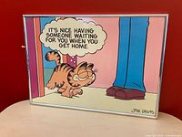 Full view of framed Garfield poster against red wall