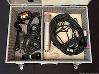 Open aluminum case showing microphone, cables, bracket, foam interior