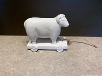 Side view of white ceramic sheep on wheeled base with jute cord