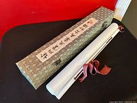 scroll rolled beside brocade box showing script label and clasp
