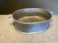 Oblique view of hammered aluminum oval roaster showing interior and one handle