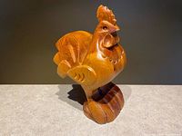 Front angled view of rooster showing body, tail and base