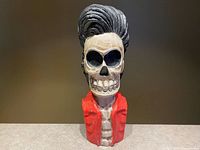 Front view of wooden skeleton bust showing skull, teeth, pompadour hair, red jacket