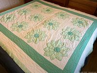 Full view of handmade green and cream Dresden Plate quilt on bed