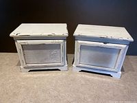 Both music boxes closed showing distressed white finish and front panels