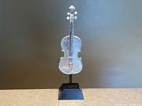 Full view of silver resin violin sculpture on black base