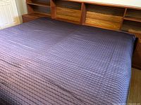 Full view of purple quilted bedspread on king bed