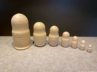 Seven nesting dolls lined up from largest to smallest closed