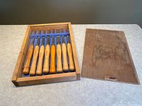 Overview of eight chisels in fitted wooden tray with lid set aside