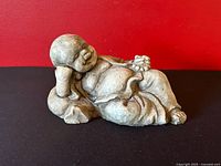 Full view reclining Buddha cement statue with grapes