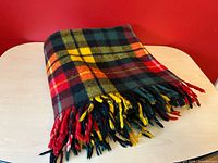 Folded tartan plaid wool blanket showing fringe and colors