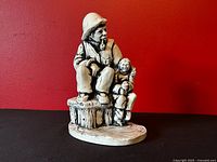Front view of soapstone sculpture showing fisherman and child on dock