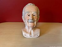 Front view of bisque shoulder head showing facial detail and assembly holes