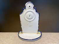 Front view showing white enamel soap dish, scalloped top, blue trim, mounting hole, wear and chips