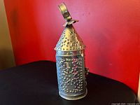 Full view of punched tin lantern against red wall