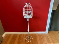 Full view of white metal birdcage stand showing cage, stem, and base