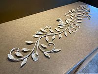 Full view of elongated white metal vine wall décor placed on countertop