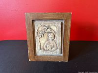 Front view of wooden box showing sculpted mother relief panel