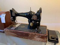 Full view of Singer sewing machine on wood base with pedal nearby