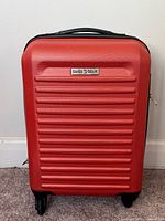 Front view of red Swiss Gear hard shell suitcase showing logo and ribbed design